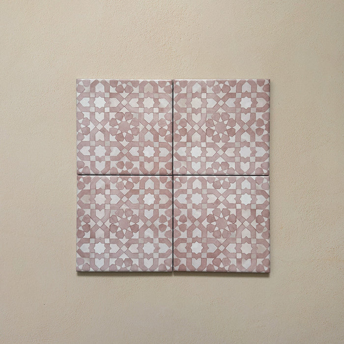 Composición de cuatro azulejos de estilo marroquí Bedouin Tetuan Rosa 15x15 cm con patrón geométrico en rosa empolvado y blanco, con acabado mate artesanal y ligera variación tonal, presentados sobre fondo neutro cálido para destacar su diseño artesanal.