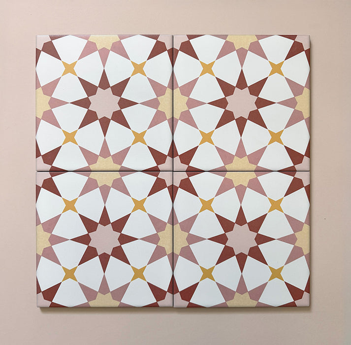 Primer plano de cuatro azulejos cerámicos de estilo marroquí Agraba Primavera 20x20 cm, destacando el patrón geométrico de estrellas en tonos terracota, rosa empolvado, mostaza y blanco sobre fondo pastel suave.