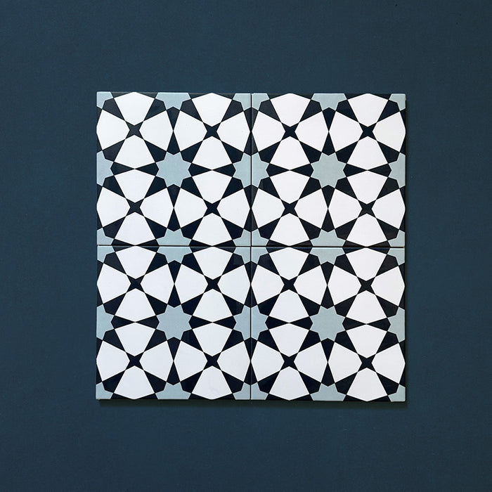 Primer plano de cuatro azulejos cerámicos de estilo marroquí Agraba Azul Blue 20x20 cm colocados juntos, mostrando un patrón geométrico de estrellas en tonos azul marino, azul claro y blanco sobre fondo azul intenso.