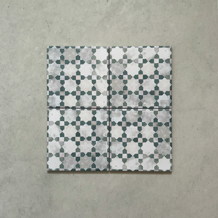Disposición de cuatro azulejos de estilo marroquí Bedouin Mequinez Verde 15x15 cm, destacando el diseño geométrico de estrellas y cruces en tonos verde suave, gris y blanco con acabado envejecido de inspiración artesanal.