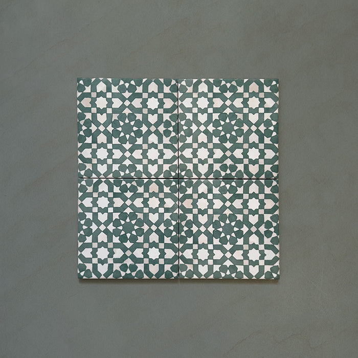 Composición de cuatro azulejos de estilo marroquí Bedouin Tetuan Verde 15x15 cm, destacando el motivo geométrico repetido de estrellas y cruces en tonos verde intenso, beige suave y blanco con acabado mate artesanal y textura sutil.