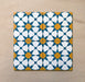 Primer plano de cuatro azulejos cerámicos de estilo marroquí Agraba Sunshine 20x20 cm colocados juntos, destacando un patrón geométrico de estrellas en azul, amarillo mostaza y blanco sobre fondo arena neutro.