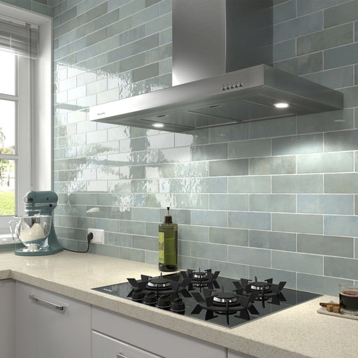 Salpicadero de cocina con azulejos de pared cerámicos Zellij Aqua Ladrillo 6,5 × 20 cm de estilo marroquí, colocados en un diseño tipo ladrillo clásico con suave variación en tonos azul verdoso y acabado brillante, combinados con encimeras claras y grifería cromada.
