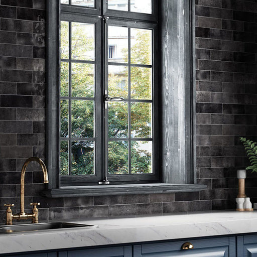 Interior de cocina con azulejos de pared cerámicos Zellij Negro Ladrillo 6,5 × 20 cm de estilo marroquí, colocados en un diseño tipo ladrillo con variación tonal en negro profundo y acabado brillante, combinados con encimeras de efecto mármol, grifería de latón y mobiliario oscuro.