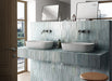 Zona de lavabo en baño con azulejos de pared cerámicos Zellij Aqua Ladrillo 6,5 × 20 cm de estilo marroquí, colocados en disposición vertical en paredes y mueble de lavabo, mostrando una suave variación en tonos azul verdoso, acabado brillante de aspecto artesanal y lavabos dobles modernos con grifería cromada.