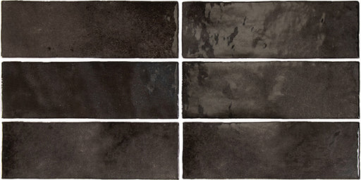 Vista cenital de azulejos de pared cerámicos Zellij Negro Ladrillo 6,5 × 20 cm de estilo marroquí, dispuestos en un patrón desplazado, mostrando una profunda variación tonal en negro, un acabado brillante de aspecto artesanal y bordes suavemente irregulares.
