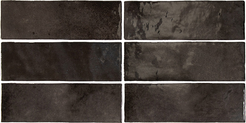 Vista cenital de azulejos de pared cerámicos Zellij Negro Ladrillo 6,5 × 20 cm de estilo marroquí, dispuestos en un patrón desplazado, mostrando una profunda variación tonal en negro, un acabado brillante de aspecto artesanal y bordes suavemente irregulares.