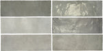 Vista cenital de azulejos de pared cerámicos Zellij Gris Ladrillo 6,5 × 20 cm de estilo marroquí, dispuestos en un patrón desplazado, mostrando una suave variación tonal en gris, un acabado brillante de aspecto artesanal y bordes ligeramente irregulares.