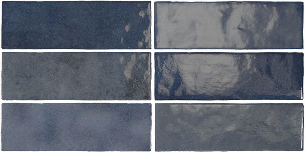Vista cenital de azulejos de pared cerámicos Zellij Azul Ladrillo 6,5 × 20 cm de estilo marroquí, dispuestos en un patrón desplazado, mostrando una profunda variación en tonos azules, un acabado brillante de aspecto artesanal y bordes suavemente irregulares.