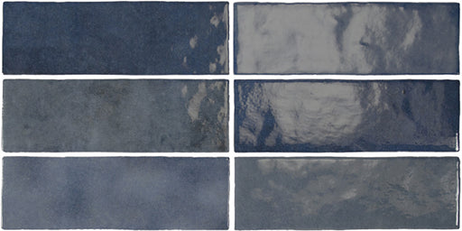 Vista cenital de azulejos de pared cerámicos Zellij Azul Ladrillo 6,5 × 20 cm de estilo marroquí, dispuestos en un patrón desplazado, mostrando una profunda variación en tonos azules, un acabado brillante de aspecto artesanal y bordes suavemente irregulares.