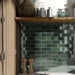 Salpicadero de cocina con azulejos de pared cerámicos Zellij Verde Musgo Ladrillo 6,5 × 20 cm de estilo marroquí, colocados en un diseño tipo ladrillo clásico con rica variación en tonos verdes, acabado brillante de aspecto artesanal y bordes suavemente irregulares, combinados con estanterías de madera cálida y materiales naturales para aportar profundidad y contraste.