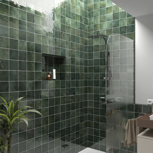 Zona de ducha en baño con azulejos de pared cerámicos Zellij Verde Musgo Cuadrado 13,2 × 13,2 cm de estilo marroquí, mostrando una rica variación en tonos verdes con acabado brillante, combinados con mampara de vidrio, nicho empotrado y ducha moderna con grifería cromada.