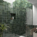 Zona de ducha en baño con azulejos de pared cerámicos Zellij Verde Musgo Cuadrado 13,2 × 13,2 cm de estilo marroquí, mostrando una rica variación en tonos verdes con acabado brillante, combinados con mampara de vidrio, nicho empotrado y ducha moderna con grifería cromada.