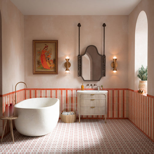 Baño con azulejos de suelo Agraba Cotto de 20 × 20 cm de estilo marroquí, combinados con azulejos de pared a rayas en tonos terracota, una bañera exenta, paredes en tonos neutros y cálidos detalles en latón.