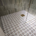 Ducha a ras de suelo con azulejos Agraba Natural de estilo marroquí en el suelo, combinados con azulejos de pared en tono verde salvia colocados en vertical, una mampara de cristal sin marco y grifería de ducha en acabado latón cepillado para crear un baño contemporáneo de inspiración mediterránea.