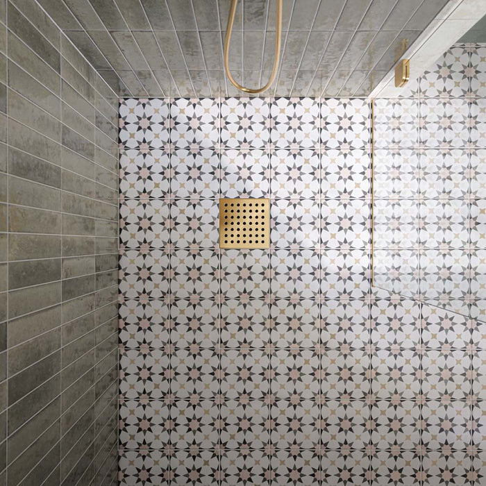 Ducha a ras de suelo con azulejos Agraba Natural de estilo marroquí en el suelo, combinados con azulejos de pared en tono verde salvia colocados en vertical, una mampara de cristal sin marco y grifería de ducha en acabado latón cepillado para crear un baño contemporáneo de inspiración mediterránea.