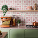 Cocina llena de color con azulejos decorados Agraba Springs de 20 × 20 cm de estilo marroquí en el salpicadero, con motivos geométricos de estrellas en tonos rosa, terracota y crema, combinados con muebles en verde salvia, utensilios de cocina de cobre y estanterías de madera.
