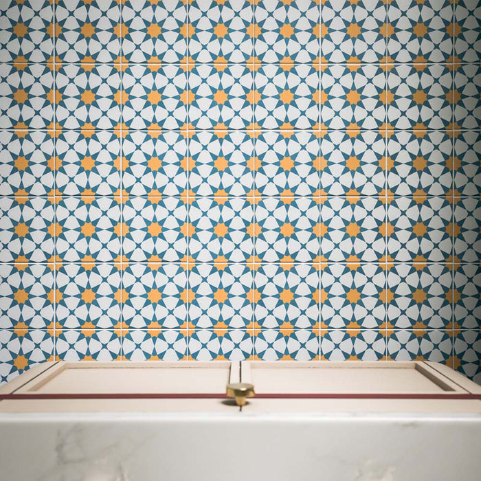 Azulejos Agraba Sunshine de 20 × 20 cm de estilo marroquí, con un patrón geométrico repetitivo de estrellas en azul intenso, blanco nítido y cálidos tonos ocre, creando una pared protagonista atrevida y llena de color.