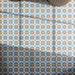 Primer plano de los azulejos de suelo Agraba Blue and Yellow de 20 × 20 cm de estilo marroquí, con llamativos motivos geométricos de estrellas en tonos azul, naranja y blanco, dispuestos en un patrón repetitivo que crea un acabado decorativo lleno de color.
