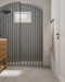 Baño con azulejos de pared Atlas Blue Mini Brick 5x15 cm en acabado brillo, instalados en disposición vertical a rayas dentro de una ducha con arco, mostrando tonos azules intensos con sutil variación tonal, combinados con suelo en tonos neutros y grifería negra.