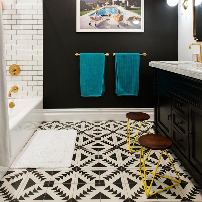 Azulejos de estilo marroquí Alhambra Alkazar 20x20 cm en un baño moderno, con patrones geométricos en blanco y negro que crean un fuerte contraste con paredes negras, grifería en latón y azulejos tipo metro en blanco.