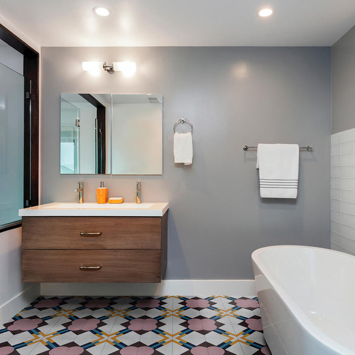 Bathroom featuring Geometry Contour 20x20cm patterned floor tiles, showcasing pink circular motifs with mustard, teal, and navy intersecting lines. Styled with a floating wooden vanity, double sinks, grey walls, chrome fixtures, and a modern freestanding bathtub for a clean contemporary look.