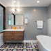 Bathroom featuring Geometry Contour 20x20cm patterned floor tiles, showcasing pink circular motifs with mustard, teal, and navy intersecting lines. Styled with a floating wooden vanity, double sinks, grey walls, chrome fixtures, and a modern freestanding bathtub for a clean contemporary look.