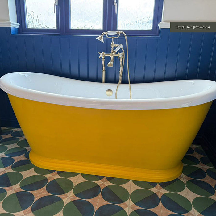 Bathroom featuring Geometry Ocean 20x20cm geometric patterned floor tiles in blue, green, and sand tones, styled with a bright yellow freestanding bath and navy panelled walls.