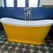 Bathroom featuring Geometry Ocean 20x20cm geometric patterned floor tiles in blue, green, and sand tones, styled with a bright yellow freestanding bath and navy panelled walls.