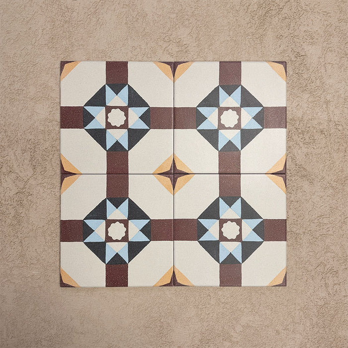 Cuatro baldosas Europa Berlin 20×20 cm de estilo Victoriano Marroquí colocadas juntas para mostrar el patrón geométrico repetitivo en forma de estrella en tonos burdeos, azul, mostaza y crema, sobre un fondo beige texturizado.