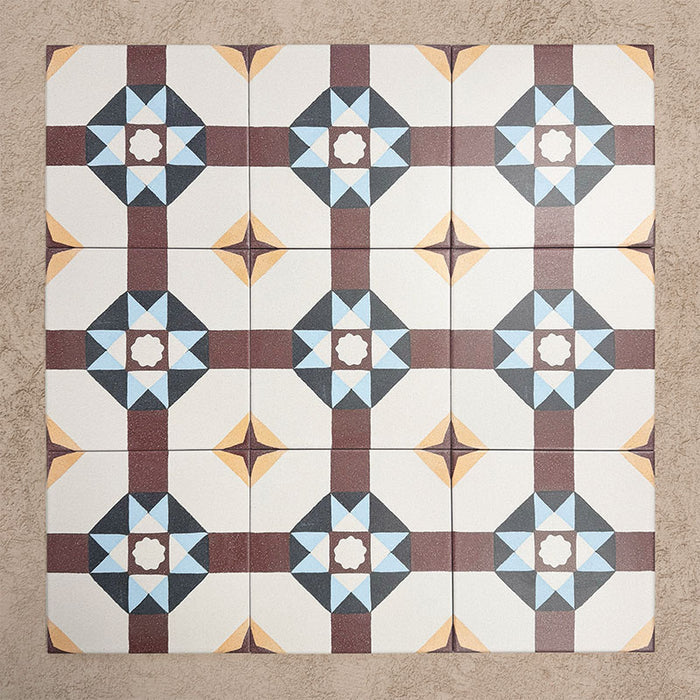 Grupo de baldosas Europa Berlin 20×20 cm de estilo Victoriano Marroquí dispuestas juntas para mostrar el patrón geométrico repetitivo en forma de estrella en tonos burdeos, azul, mostaza y crema, sobre un fondo beige texturizado.