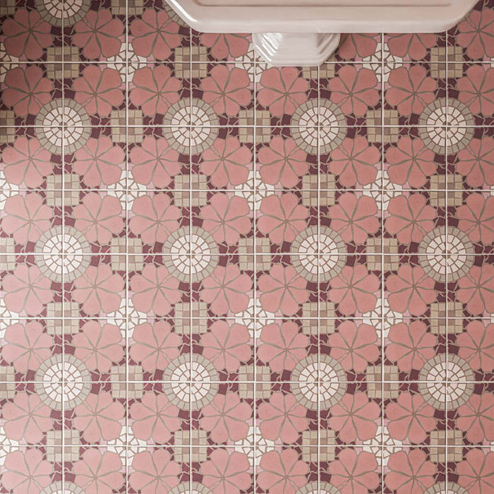 Primer plano de los azulejos de suelo Nantes Rose Pink de 20 × 20 cm de estilo marroquí, con delicados motivos florales en tonos rosa, detalles en burdeos y elementos geométricos en color crema, dispuestos en un patrón decorativo que se repite por toda la superficie.