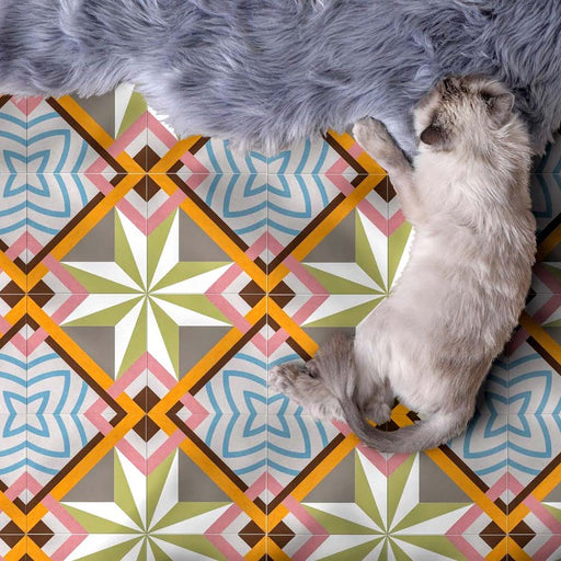Baldosas cerámicas Cabana Star de estilo marroquí 20x20 cm para suelo, con diseño geométrico multicolor, mostradas junto a un gato descansando sobre una alfombra gris suave.
