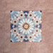 Arrangement of Fizaan Fiera 20x20cm Moroccan-style porcelain tiles, showcasing a repeating geometric pattern in soft blue, red and neutral tones.