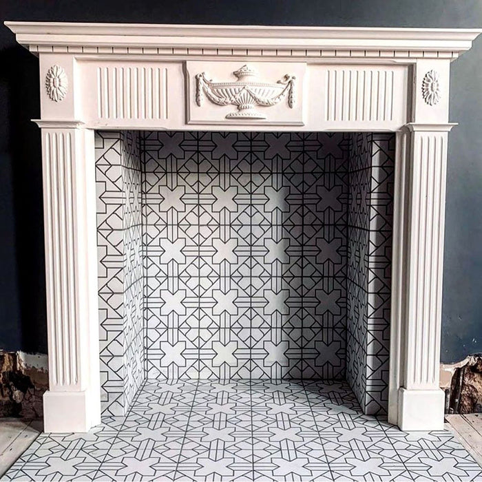 Azulejos de estilo marroquí Alhambra Palacio 20x20 cm colocados en el interior de una chimenea blanca clásica, mostrando un elegante patrón geométrico en cruz en blanco y negro que aporta un contraste contemporáneo a un entorno tradicional.