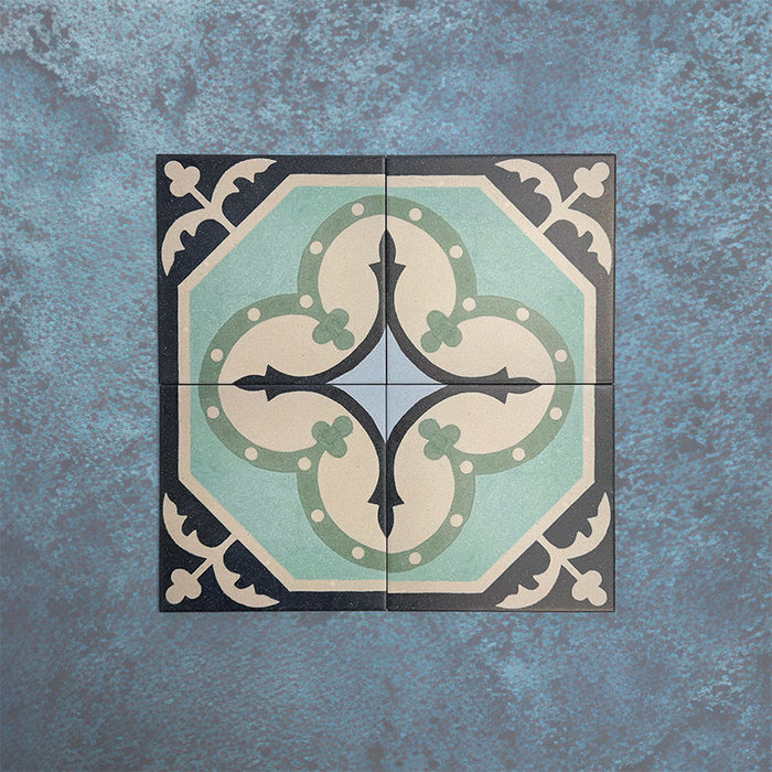 Cuatro baldosas Europa Gothenberg 20 × 20 cm de estilo Victoriano Marroquí colocadas juntas sobre un fondo azul texturizado, formando un patrón geométrico simétrico en tonos azul, verde menta y crema.