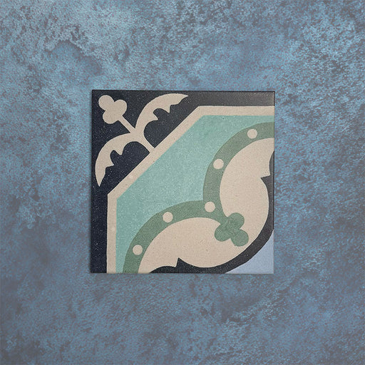 Baldosa Europa Gothenberg 20 × 20 cm de estilo Victoriano Marroquí mostrada individualmente sobre un fondo azul texturizado, con un patrón geométrico de esquina en tonos azul, verde menta y crema en una imagen de producto en primer plano.