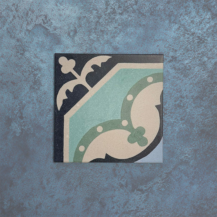Baldosa Europa Gothenberg 20 × 20 cm de estilo Victoriano Marroquí mostrada individualmente sobre un fondo azul texturizado, con un patrón geométrico de esquina en tonos azul, verde menta y crema en una imagen de producto en primer plano.