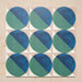 Group image showing nine Geometry Ocean 20x20cm geometric patterned tiles arranged in a grid, featuring blue and green semicircles on a sand and white background, photographed against a neutral stone surface.