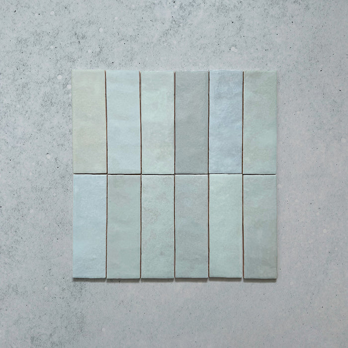 Vista cenital de azulejos de pared cerámicos Zellij Aqua Ladrillo 6,5 × 20 cm de estilo marroquí, dispuestos en un patrón alineado, destacando la suave variación tonal azul verdosa, el acabado brillante artesanal y los bordes sutilmente irregulares.