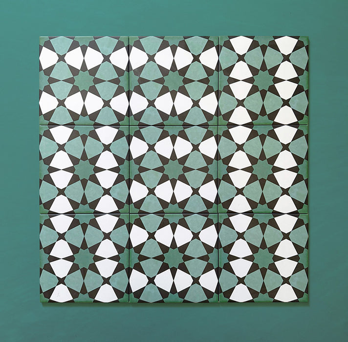 Cuatro azulejos de estilo marroquí Agraba Verde 20x20 cm presentados sobre fondo verde azulado, mostrando el patrón geométrico repetido en verde y blanco para un acabado clásico de inspiración artesanal.