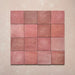 Vista cenital de azulejos de pared cerámicos Zellij Rosa Ladrillo 6,5 × 20 cm de estilo marroquí, dispuestos en cuadrícula, mostrando una suave variación tonal, bordes ligeramente irregulares y un acabado brillante con efecto artesanal en tonos rosados sobre un fondo texturizado.