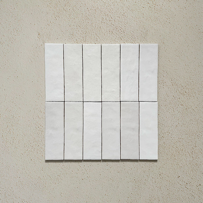 Vista cenital de azulejos de pared cerámicos Zellij Blanco Ladrillo 6,5 × 20 cm de estilo marroquí en color blanco, dispuestos en un patrón vertical alineado, destacando la ligera variación tonal y el efecto artesanal sobre un fondo neutro.