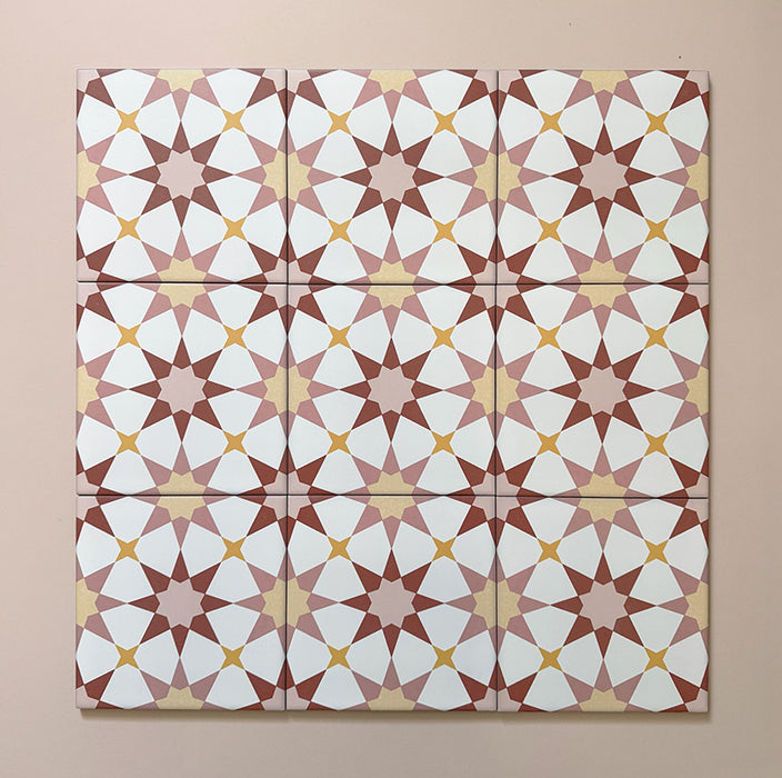 Primer plano de varios azulejos cerámicos de estilo marroquí Agraba Primavera 20x20 cm colocados en cuadrícula, mostrando un patrón geométrico de estrellas en terracota, rosa empolvado, mostaza y blanco sobre fondo pastel suave.