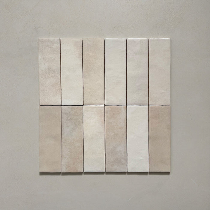 Vista cenital de azulejos de pared cerámicos Zellij Ocre Ladrillo 6,5 × 20 cm de estilo marroquí, dispuestos en cuadrícula, mostrando una suave variación tonal, bordes irregulares y un acabado brillante con efecto artesanal en tonos neutros cálidos sobre un fondo liso.