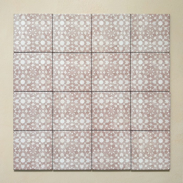 Conjunto de azulejos de estilo marroquí Bedouin Tetuan Rosa 15x15 cm dispuestos en composición cuadrada, mostrando un patrón geométrico de estrellas en rosa empolvado y blanco con acabado mate artesanal, creando un efecto mosaico suave y decorativo sobre fondo beige cálido.