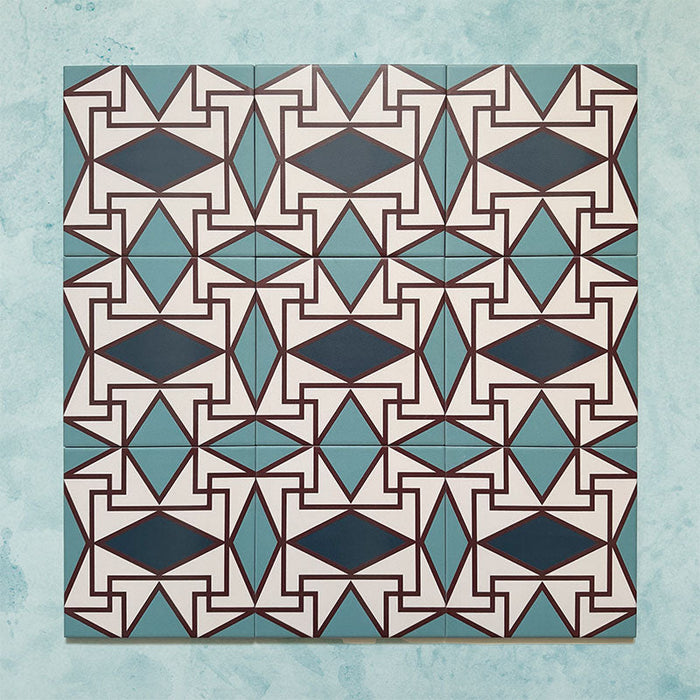 Group image showing multiple Geometry Iris 20x20cm patterned tiles arranged in a repeating layout, featuring an intricate geometric design in teal, navy, terracotta-red, and cream, photographed against a soft mottled aqua background.