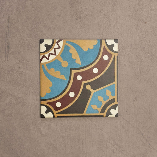 Baldosa Europa Hanover 20 × 20 cm de estilo Victoriano Marroquí mostrada individualmente sobre un fondo beige texturizado, con un patrón geométrico y floral decorativo en tonos azul, terracota, mostaza y crema en una imagen de producto en primer plano.