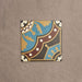 Baldosa Europa Hanover 20 × 20 cm de estilo Victoriano Marroquí mostrada individualmente sobre un fondo beige texturizado, con un patrón geométrico y floral decorativo en tonos azul, terracota, mostaza y crema en una imagen de producto en primer plano.