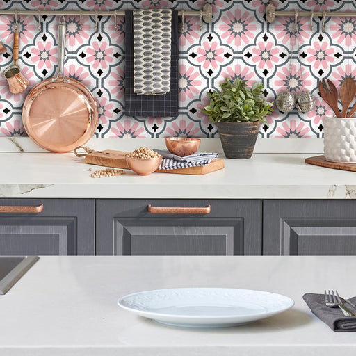 Salpicadero de cocina con baldosas porcelánicas Clarence Rose 20x20 cm de estilo victoriano marroquí en tonos rosa suave y gris, combinadas con mobiliario gris, encimeras blancas y detalles en cobre para crear una pared decorativa con carácter.